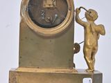 a gold clock with a cheroon and a cupid on it