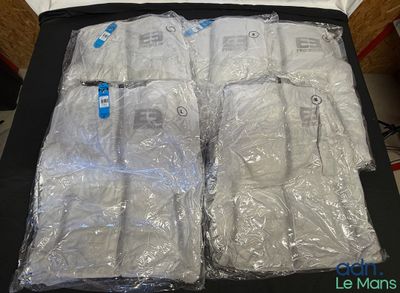 a black suitcase filled with bags of white shirts