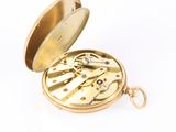 a gold pocket watch inside of a case on a white surface