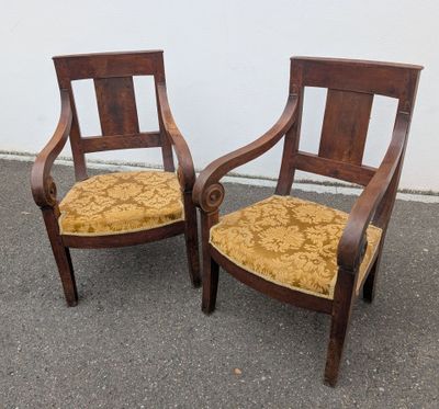 two wooden chairs with yellow upholstered cushions sit in front of a white wall