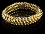 gros plan d'un bracelet en or sur une surface noire