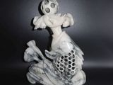 une figurine représentant un poisson sur lequel est perché un homme