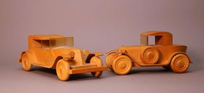 two wooden toy cars sitting side by side on a table