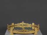 une couronne en or posée sur un socle blanc, sur fond noir
