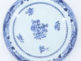 blue and white plate with flowers and birds on it on a white surface