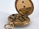 an image of a gold pocket watch sitting on a white surface