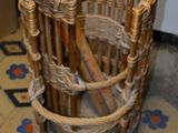 un panier en osier posé par terre, contenant un parapluie