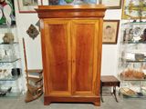 a wooden cabinet with glass shelves and pictures on the wall