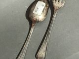 two silver spoons and a fork on a table