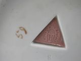 a small triangle on a plate that has a stamp on it