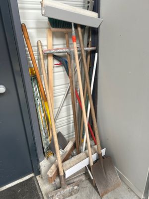 un tas de balais et une pelle devant la porte d'un garage