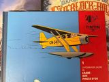two books on a wooden table with a plane flying over them