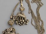 pair of antique silver jhuma earrings and a gold chain necklace