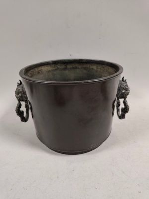 a black pot with two handles on a white surface