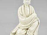 a white figurine of a man sitting in a meditation position