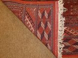 an image of a red rug with fringes on top of it