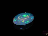 an image of a black opal with green and yellow lights