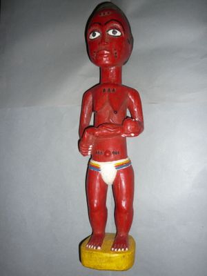 une statue en bois rouge représentant un homme torse nu