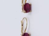 two pairs of earrings with red stones on them on a white surface