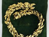 a close up of a green velvet bag with a gold wreath on it
