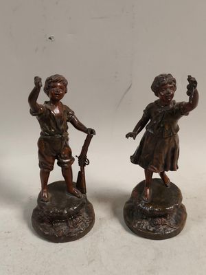 pair of bronze figurines of a boy and a girl with a gun