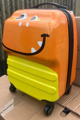 une valise sur laquelle est dessiné un visage souriant, posée sur un carton