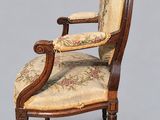 an old chair with a floral upholstered back and arms