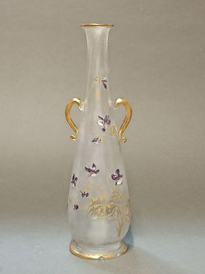 un vase en verre muni d'une anse dorée, posé sur une table