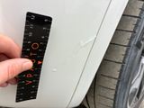 a hand that is holding a ruler next to a car