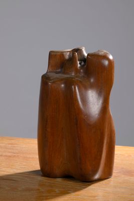 a wooden sculpture on a table with a gray background