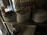 several plates and pans are stacked on a shelf in a kitchen