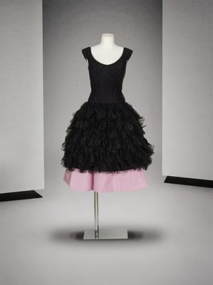 une robe noire et rose posée sur un mannequin devant un mur blanc