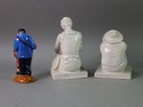 three figurines of a man and a woman sitting on a bench