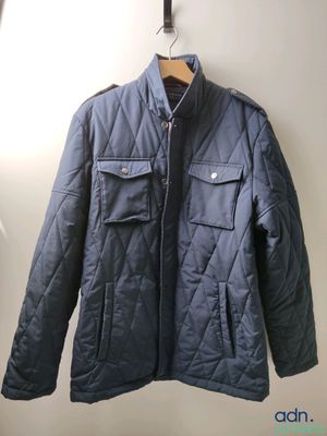 blue quilted jacket hanging on a hanger in a white room