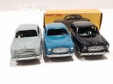 three toy cars are sitting in front of a box on a white surface