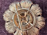 broche en argent et en or, de forme circulaire, posée sur un tissu violet