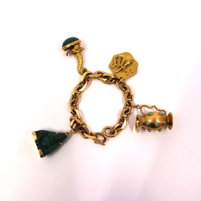 un gros plan d'un bracelet en or orné de breloques sur fond blanc