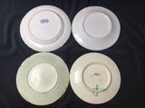 three white plates with green handles are sitting on a black cloth