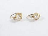 une paire de boucles d'oreilles en perles et en or posées sur une surface blanche