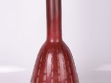 un vase rouge posé sur une surface blanche