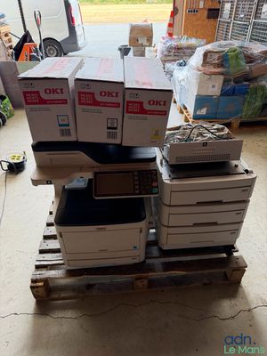 une pile d'imprimantes posée sur une palette dans un garage