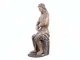 a statue of a man sitting on top of a wooden block