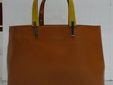 tan and yellow leather handbag with two handles on a white surface