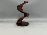 une image représentant une sculpture d'un escalier en colimaçon posée sur un socle en bois