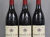 Trois bouteilles de vin rouge sont alignées sur une table en verre