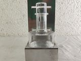 a small glass bottle with a metal holder on a table