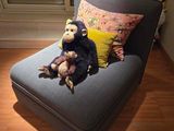 un singe en peluche assis sur une chaise dans un coin de la pièce