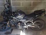 une moto noire garée dans un garage, près d'un mur de briques