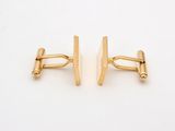 two pairs of gold cufflinks on a white surface