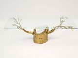 a glass table with a gold base and a tree branch on it